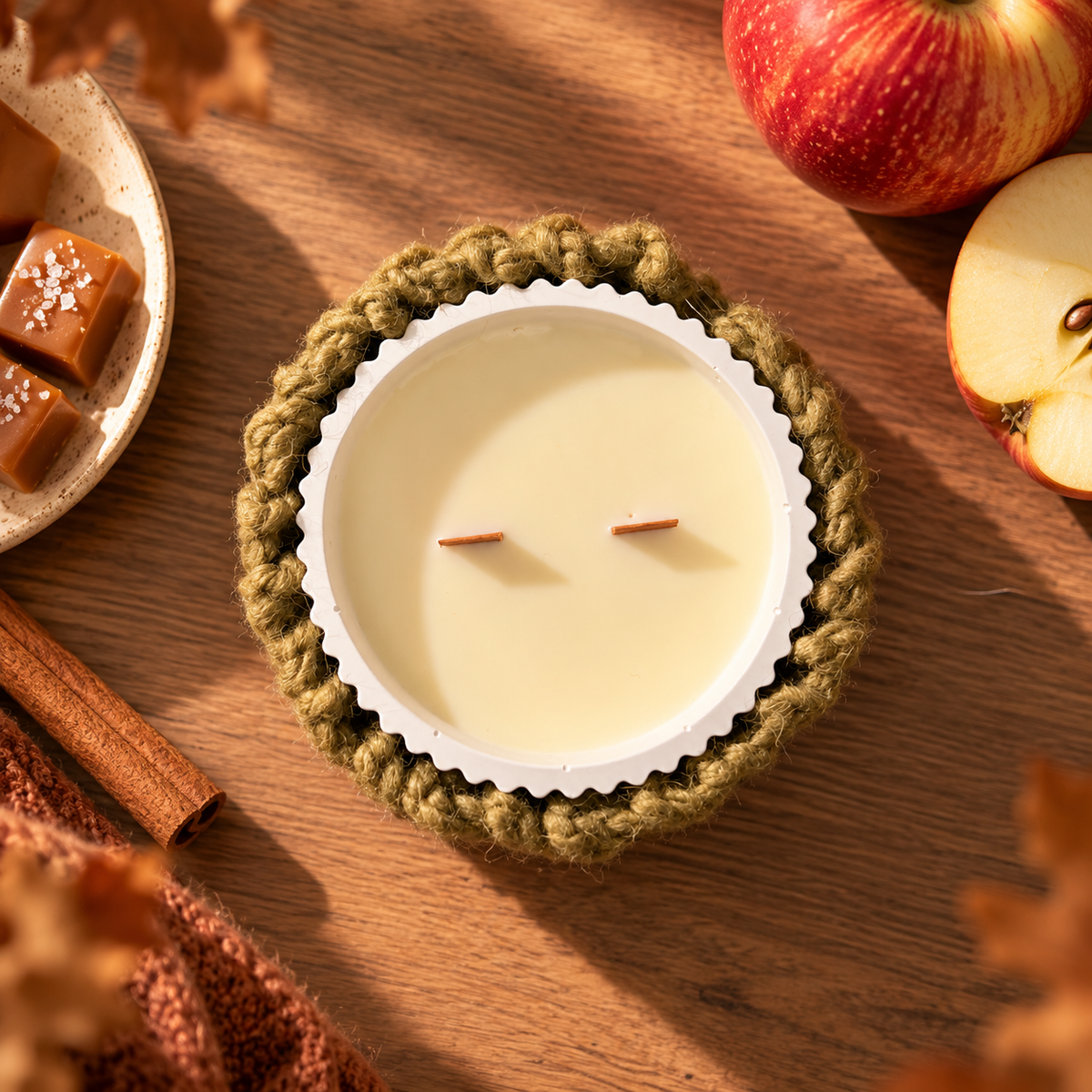 Vela de soja aroma Manzana Caramelizada con doble mecha de madera y funda de lana de algodón tejida a mano, en ambiente cálido de otoño.