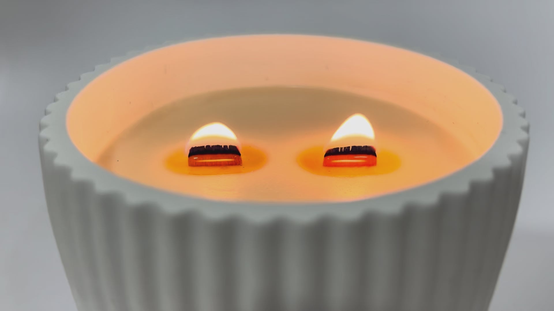 Vela aromática de soja natural encendida con pabilo de madera crepitante en cuenco cerámico artesanal
