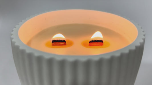 Vela aromática de soja natural encendida con pabilo de madera crepitante en cuenco cerámico artesanal
