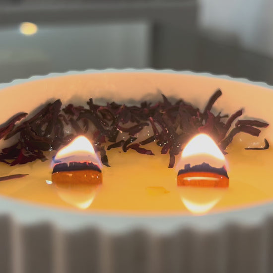 video de vela aromatica de soja de hibisco,loto y sándalo encendida con doble mecha de madera crepitante y cera fundida co adorno de flor de hibisco