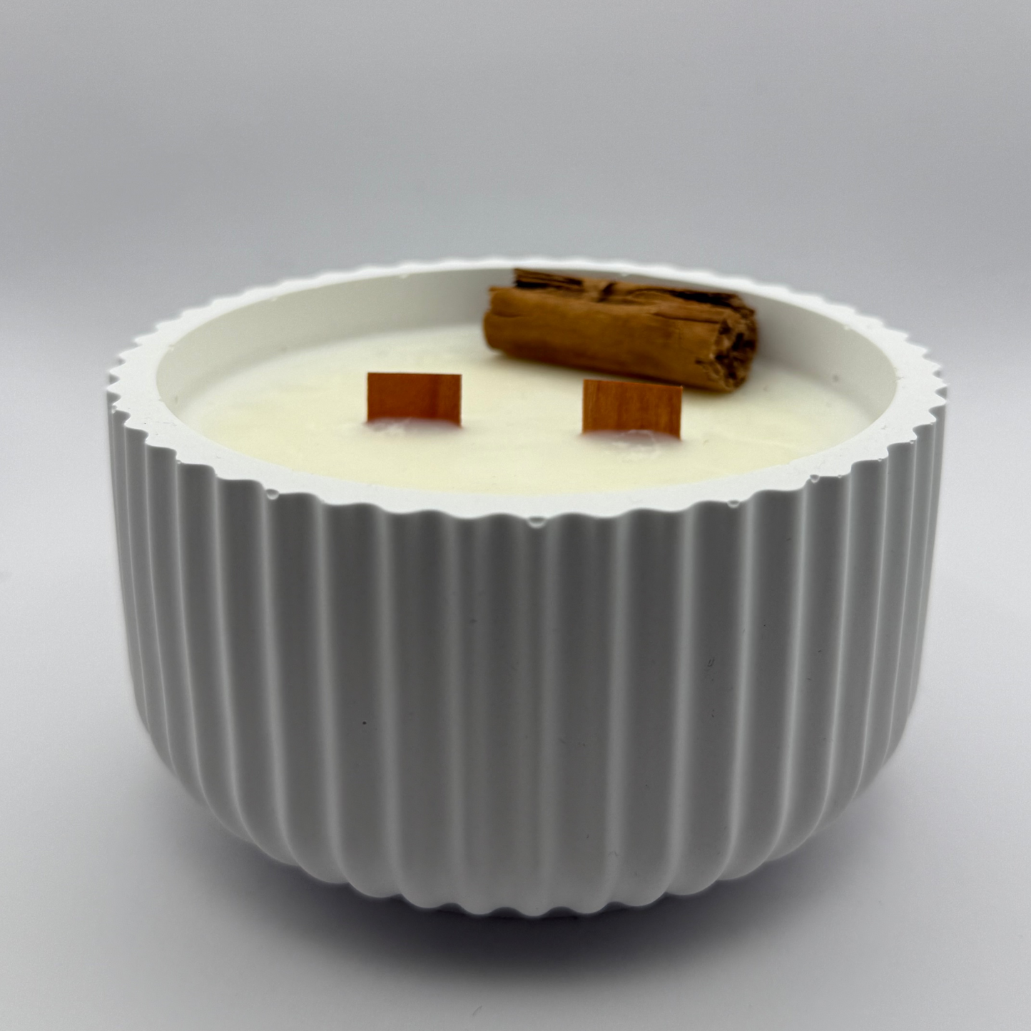 vela aromática Cinnamon Roll de canela en cera de soja con mecha de madera en recipiente cerámico blanco
