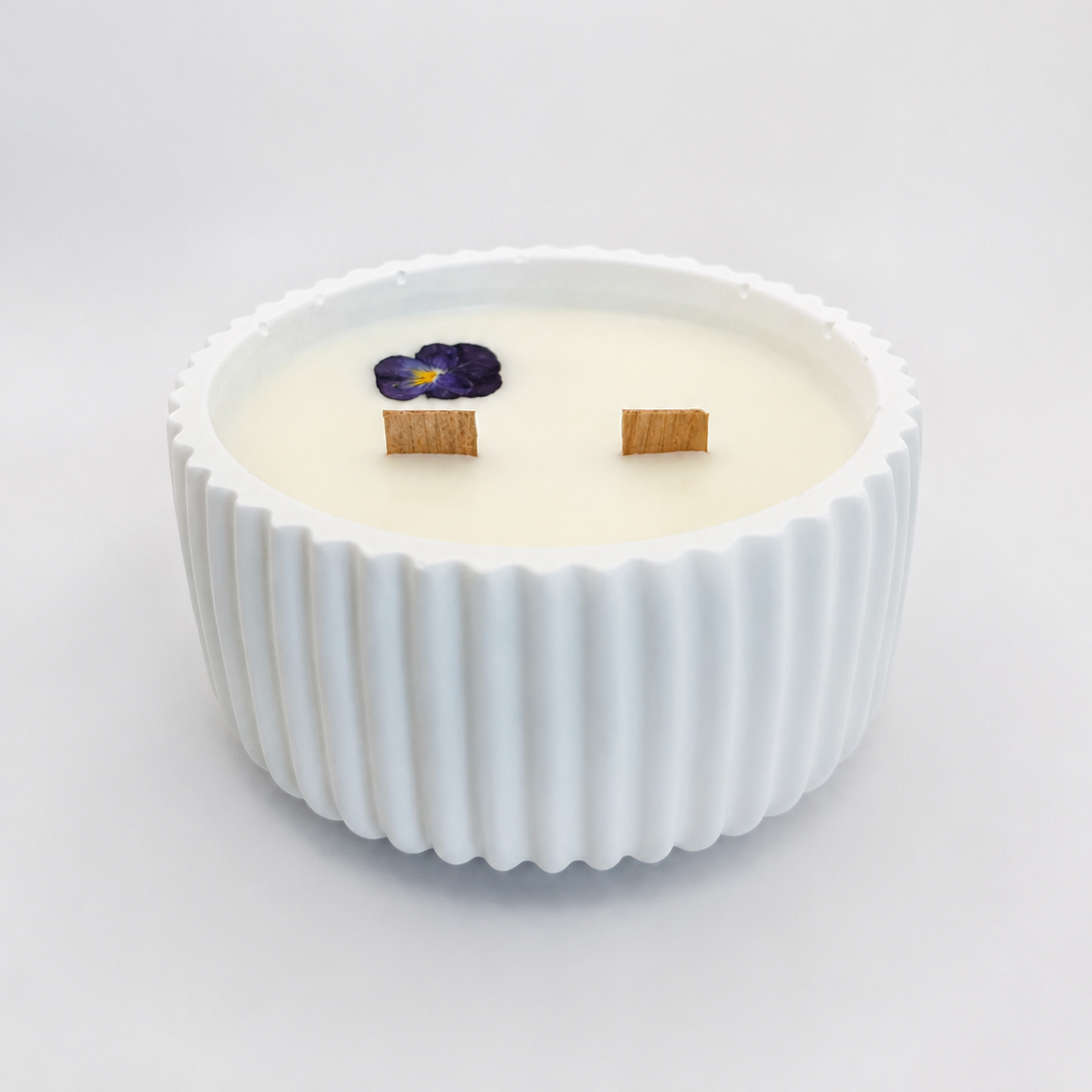 Vista lateral de vela aromática de violeta y vainilla blanca con cera de soja 100% natural, doble mecha de madera y decoración de flor violeta prensada artesanal.